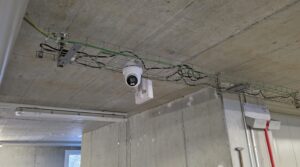 Weisse Hikvision-ColorVu-Turret-Kamera an der Betondecke ueber einer Kabelpritsche im Lager