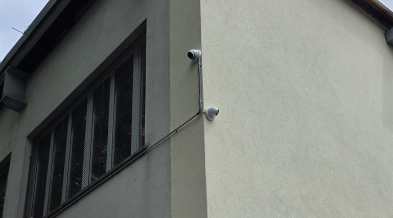 Hikvision Dome-Kamera hoch an verputzter Gebäudeecke mit Hinweißchild zur Videoüberwachung