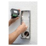 Monteur setzt den Aufputz-Rahmen einer Hikvision Türsprechanlage an der Hauswand